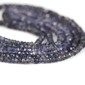 May include: A strand of dark blue faceted gemstone beads. The beads are small and have a slightly irregular shape.