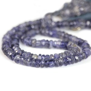 May include: A strand of dark blue gemstone beads. The beads are faceted and have a slightly irregular shape. The beads are strung on a clear thread.
