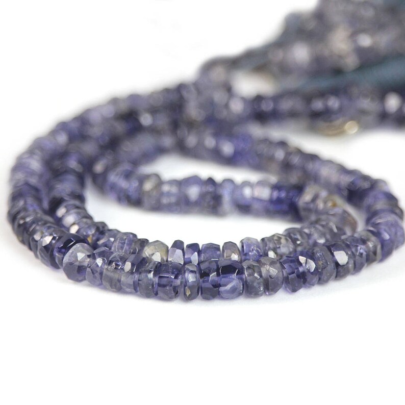 May include: A strand of dark blue gemstone beads. The beads are faceted and have a slightly irregular shape. The beads are strung on a clear thread.