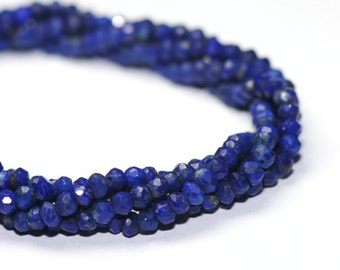 May include: A strand of deep blue lapis lazuli beads, each bead is faceted and has a slightly irregular shape. The beads are strung together to form a long necklace.
