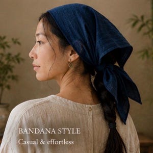 May include: A dark blue bandana made of a textured fabric tied at the back of the head. The bandana features a subtle grid pattern and is worn over dark hair. The text BANDANA STYLE and Casual & effortless are printed on the lower left side.
