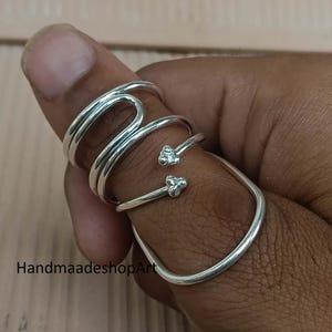 Könnte beinhalten: Eine weiße Keramik-Tasse mit schwarzem Henkel und dem Text "But First, Coffee" in handschriftlichem Stil. Die Tasse steht auf einer weißen Oberfläche. Die Tasse ist etwa 10 cm hoch.