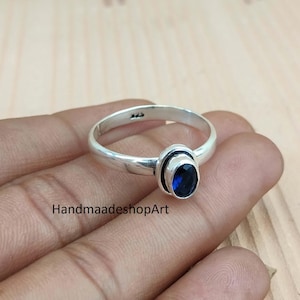 May include: A silver ring with a dark blue oval gemstone. The ring has a simple band and a bezel setting for the stone. The text "HandmaadeshopArt" is visible in the image.