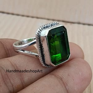 May include: A sterling silver ring featuring a large, emerald-cut, deep green gemstone. The ring has a textured bezel setting and a split shank design. The inscription "925" is visible on the band. The text "HandmaadeshopArt" is also visible.