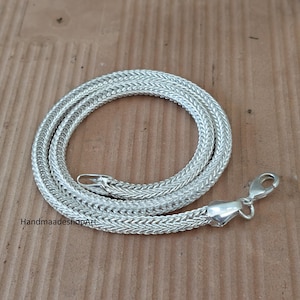 May include: A silver-toned chain necklace featuring a tightly woven, rounded wheat or foxtail link pattern. The necklace includes a polished metal lobster claw clasp at one end and a small loop at the other. The text HandmaadeshopArt is visible.