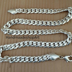 Può includere: Un bracciale a catena a maglia a catena argentata con chiusura a moschettone. Il bracciale è composto da maglie ovali ad incastro. Il testo "HandmaadeshopArt" è stampato sulla superficie.