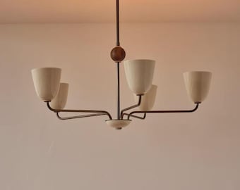 May include: A mid-century modern chandelier with five off-white cone-shaped shades. The fixture has a dark brown metal frame with a wooden sphere detail and a circular ceiling mount. The arms extend horizontally, creating a balanced design.
