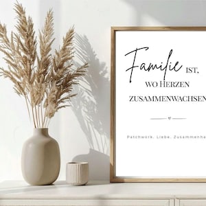 Könnte beinhalten: Ein gerahmter Druck mit den Worten "Familie ist, wo Herzen zusammenwachsen" in schwarzer Schrift. Der Druck befindet sich in einem hellen Holzrahmen und steht auf einer weißen Oberfläche. Eine Vase mit getrockneten Pflanzen und eine kleine strukturierte Tasse daneben.
