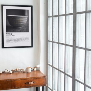K&ouml;nnte beinhalten: Ein gerahmter Schwarz-Wei&szlig;-Druck einer japanischen Kintsugi-Schale. Der Druck h&auml;ngt an einer wei&szlig;en Wand &uuml;ber einer braunen Lederkonsole. Der Text "kintsugi" befindet sich oben auf dem Druck.