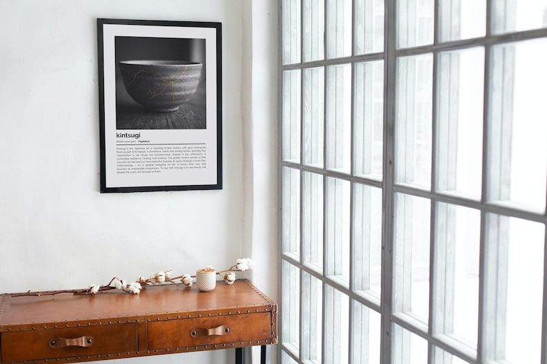 K&ouml;nnte beinhalten: Ein gerahmter Schwarz-Wei&szlig;-Druck einer japanischen Kintsugi-Schale. Der Druck h&auml;ngt an einer wei&szlig;en Wand &uuml;ber einer braunen Lederkonsole. Der Text "kintsugi" befindet sich oben auf dem Druck.
