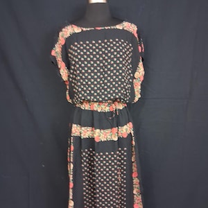 May include: Black dress with a floral pattern and a drawstring waist. The dress features a square neckline and short sleeves. The floral pattern includes pink and peach-colored flowers. The dress is displayed on a mannequin.