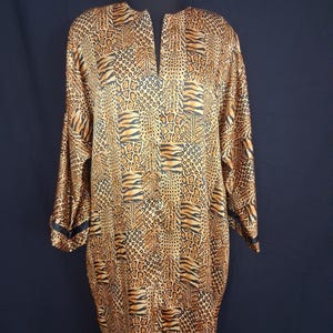 May include: A long-sleeved, knee-length dress with a V-neck and a bold animal print. The dress features a mix of leopard and tiger stripe patterns in shades of brown, black, and tan. Black trim accents the cuffs.