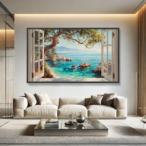 May include: A rectangular wall art piece featuring an open window view of a turquoise ocean, rocky coastline, and a tree branch extending across the top. The painting is framed in a dark border and displayed above a beige sofa in a room.