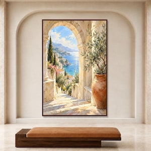 Op de afbeelding: Een rechthoekige wandkunstprint met een mediterrane kustscène gezien door een stenen boog. Het schilderij toont een terracotta pot met een olijfboom, stenen trappen, witte gebouwen en een blauwe zee onder een zonnige lucht.
