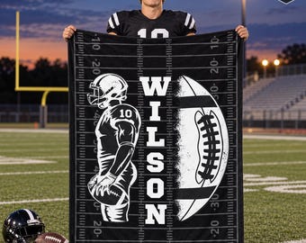 May include: A black fleece blanket featuring a white graphic of a football player wearing number 10, a football, and the name WILSON. The design includes a football field yard line pattern. A badge in the corner reads SENIOR NIGHT GIFT.