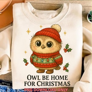 May include: Cream-colored sweatshirt featuring a cartoon owl wearing a red hat and sweater with Christmas lights. The text "OWL BE HOME FOR CHRISTMAS" is printed below the owl. Holly sprigs and gold stars decorate the design.