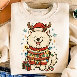 May include: Cream-colored sweatshirt featuring a smiling cartoon dog wearing a Santa hat and reindeer antlers. The dog is adorned with a festive sweater and Christmas lights. Presents and a candy cane are also included in the design.