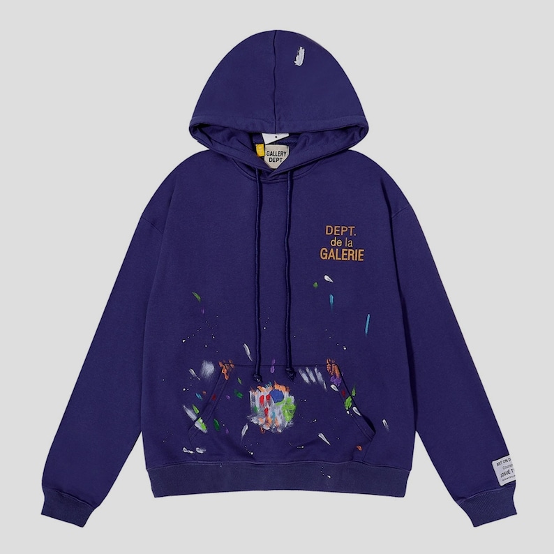 Peut inclure: Un sweat &agrave; capuche bleu marine avec une capuche &agrave; cordon et une poche kangourou. Le devant porte l'inscription "DEPT. de la GALERIE" en orange, avec des &eacute;claboussures de peinture color&eacute;es. Une petite &eacute;tiquette est sur la manche gauche. Le sweat est ample.