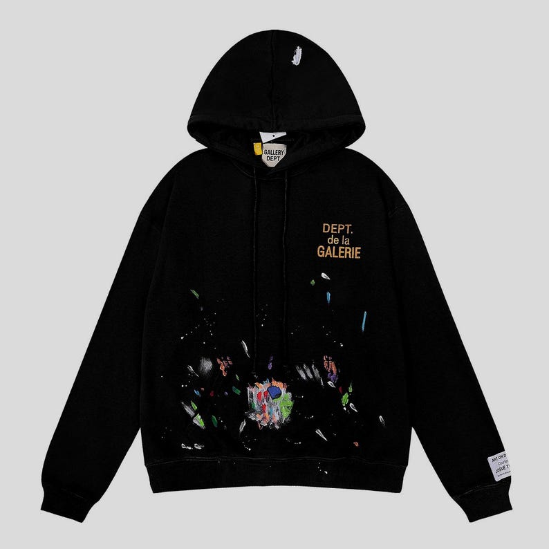 Peut inclure: Sweat-shirt &agrave; capuche noir avec un motif &eacute;clabouss&eacute; de peinture. Il pr&eacute;sente le texte "DEPT. de la GALERIE" en or sur le devant. Le capuchon porte le texte "GALLERY DEPT." en blanc. Une &eacute;tiquette est visible sur la manche.