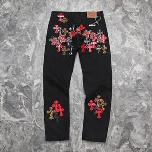 Puede incluir: Vaqueros de mezclilla negros con bordados de rosas rojas y dise&ntilde;os de cruces. Los vaqueros presentan un corte de pierna recta y parches decorativos con detalles de estampado de leopardo. Dise&ntilde;o cl&aacute;sico de cinco bolsillos.