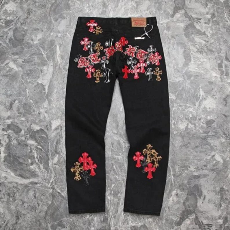 Puede incluir: Vaqueros de mezclilla negros con bordados de rosas rojas y dise&ntilde;os de cruces. Los vaqueros presentan un corte de pierna recta y parches decorativos con detalles de estampado de leopardo. Dise&ntilde;o cl&aacute;sico de cinco bolsillos.