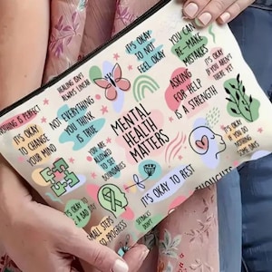 May include: A cream-colored zippered pouch with the words "Mental Health Matters" and other positive affirmations in various colors. The pouch features illustrations of a butterfly, rainbow, and puzzle pieces.