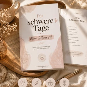 Könnte beinhalten: Ein Selbstpflege-Workbook mit dem Titel "Für schwere Tage" (Für schwierige Tage) mit dem Label "Mini Selfcare Kit". Das Cover zeigt weiche rosa Aquarelldesigns und Text. Das offene Buch zeigt eine "5-Minuten-Reset"-Checkliste.
