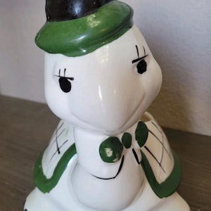 Maceta grande de cerámica vintage con forma de tortuga, sombrero de copa y pajarita, esmaltada en verde y blanco.