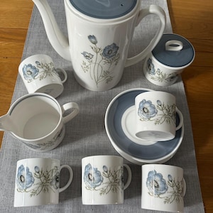 May include: A white porcelain tea set with a blue floral pattern. The set includes a teapot, sugar bowl, creamer, cups, and saucers. The teapot has a blue lid and handle. The cups and sugar bowl have matching lids.