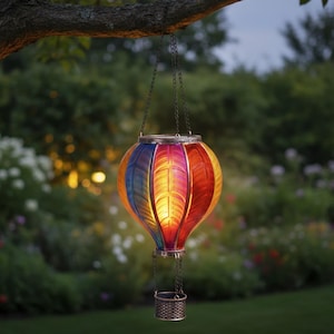May include: A colorful hot air balloon-shaped hanging lantern. The lantern features a vibrant design with sections of blue, yellow, red, and purple. It has a metal basket and is suspended by chains from a tree branch, creating a decorative outdoor lighting element.