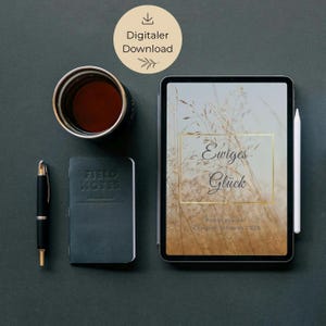 Könnte beinhalten: Draufsicht eines Arbeitsplatzes mit einem Tablet, das die Worte "Ewiges Glück" in goldfarbenen Buchstaben zeigt, einem schwarzen Stift, einem kleinen Notizbuch und einer Tasse Kaffee. Ein "Digitaler Download"-Symbol ist oben.