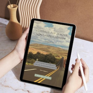 May include: A tablet displaying a journal cover with the text "VERTRAUE AUF JEHOVA VON GANZEM HERZEN" and "SPRUCHE 3:5". The cover features a road leading to a distant mountain range. A white stylus is held near the tablet.