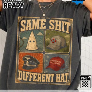 May include: A charcoal gray t-shirt featuring a graphic design with the text SAME SHIT DIFFERENT HAT. The design includes four panels displaying a white hood, a tan cap with a confederate flag, a black military-style cap with a skull, and a red cap.