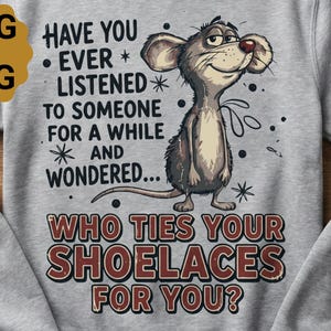 Könnte beinhalten: Hellgraues Sweatshirt mit dem Text "HAST DU JE ZUGEHÖRT, WIE SICH JEMAND FÜR EINE WEILE UND GEWUNDERT... WER DIR DIE SCHUHRIEMEN BINDET?" und einer Cartoon-Maus-Illustration.