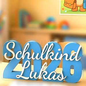 Könnte beinhalten: Ein blau-weißes 'Schulkind 2020 Lukas' Schild, eine deutsche Flagge und ein Poster mit einem Cartoon-Bären, der Schultaschen hält, mit dem Text 'Willkommen in der 1. Klasse'. Das Bild hat ein Einschulungsthema.