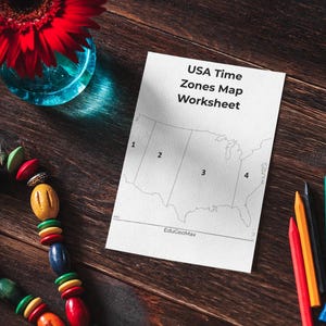 May include: A worksheet titled 'USA Time Zones Map' with a map of the United States, numbered 1-4. A red flower in a blue vase, a colourful beaded necklace, and coloured pencils are on a wooden surface.