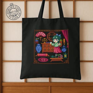 Puede incluir: Bolso tote negro con un dise&ntilde;o de pixel art de una mujer con vestimenta tradicional, rodeada de varios objetos. El dise&ntilde;o incluye una balanza, jarrones y un juego de t&eacute;. El bolso tambi&eacute;n tiene un logotipo circular que dice "Goblin's Cave Club".
