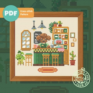Könnte beinhalten: Kreuzstichmuster mit einer Cafészene mit einem Hunde-Barista hinter einer grünen Theke. Das Design umfasst ein Fenster, Regale mit Pflanzen und den Text "PDF Cross-stitch Pattern". Das Kunstwerk ist in einem Holzrahmen gerahmt.
