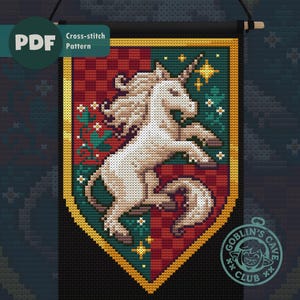 May include: Cross-stitch pattern featuring a white unicorn on a shield-shaped banner. The banner has a red and green background with gold trim. The text "PDF Cross-stitch Pattern" is in the upper left corner. The Goblin's Cave Club logo is in the lower right corner.