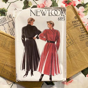 May include: A New Look 6893 sewing pattern envelope featuring illustrations of a long-sleeved, belted coat dress in black and red. The white paper envelope displays the pattern number and includes folded brown paper pattern pieces underneath.