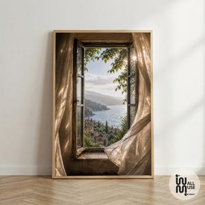 May include: A framed wall art print depicting an open window with sheer, flowing curtains. The view through the window shows a coastal landscape with a blue sea, distant mountains, and green foliage under a bright sky. The print includes the text Wall Muse.