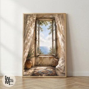 May include: A framed wall art print depicting an open window overlooking a blue sea. The scene features sheer white curtains, a terracotta pot with a green plant, and a patterned rug on the floor. The light creates soft shadows across the room.