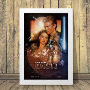 May include: A framed movie poster for Star Wars: Episode II - Attack of the Clones. The poster features Anakin Skywalker, Padmé Amidala, Obi-Wan Kenobi, and a clone trooper. The title is prominently displayed with a red and orange background.