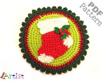May include: A crocheted Christmas coaster featuring a red stocking with white trim and a green holly sprig. The coaster has a green and red circular design with a scalloped edge. The words "PDF Pattern" are in the upper right corner.