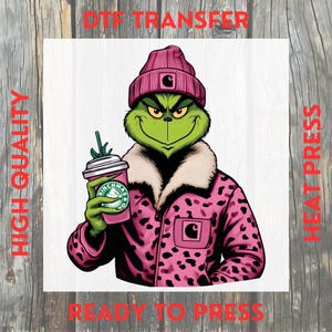 May include: A DTF transfer featuring a green Grinch character wearing a pink beanie and jacket with a leopard print design. The Grinch is holding a pink coffee cup with a green logo. The words "HIGH QUALITY" and "READY TO PRESS" are printed on the image.