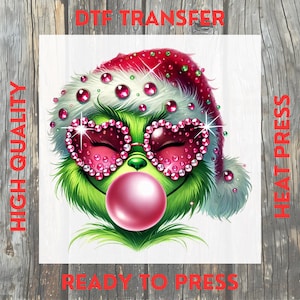 May include: A green cartoon character wearing a Santa hat and heart-shaped sunglasses, blowing a bubblegum bubble. The image has text that reads "DTF TRANSFER", "HIGH QUALITY", "HEAT PRESS", and "READY TO PRESS".