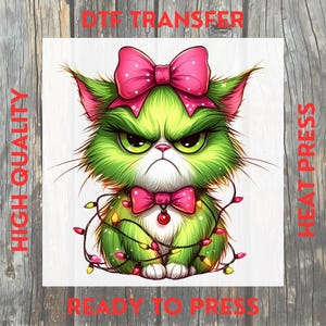 May include: A grumpy green cat with a pink bow on its head and a matching bow tie. The cat is wrapped in a string of colorful Christmas lights. The words "HIGH QUALITY", "DTF TRANSFER", "READY TO PRESS", and "HEAT PRESS" are printed in red.