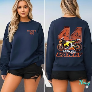 May include: Navy blue sweatshirt with the name "CANET" and the number "44" printed in orange. The back of the sweatshirt features a motorcycle graphic with the name "ARON CANET" and the number "44" in orange.