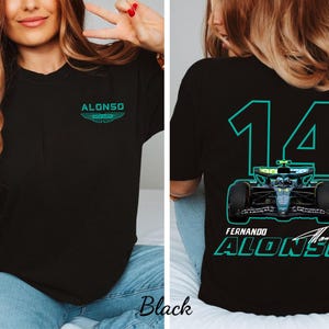 Puede incluir: Camiseta negra con diseño turquesa y blanco. La parte delantera muestra el nombre "ALONSO" sobre un logotipo. La parte trasera muestra el número "14", un gráfico de coche de carreras y "FERNANDO ALONSO".