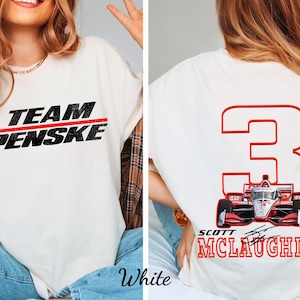 May include: Cream-coloured t-shirt with "TEAM PENSKE" in black text and a red stripe. The back displays a red number 3 with a race car graphic and "SCOTT MCLAUGHLIN" in red text. A casual, sporty apparel item.